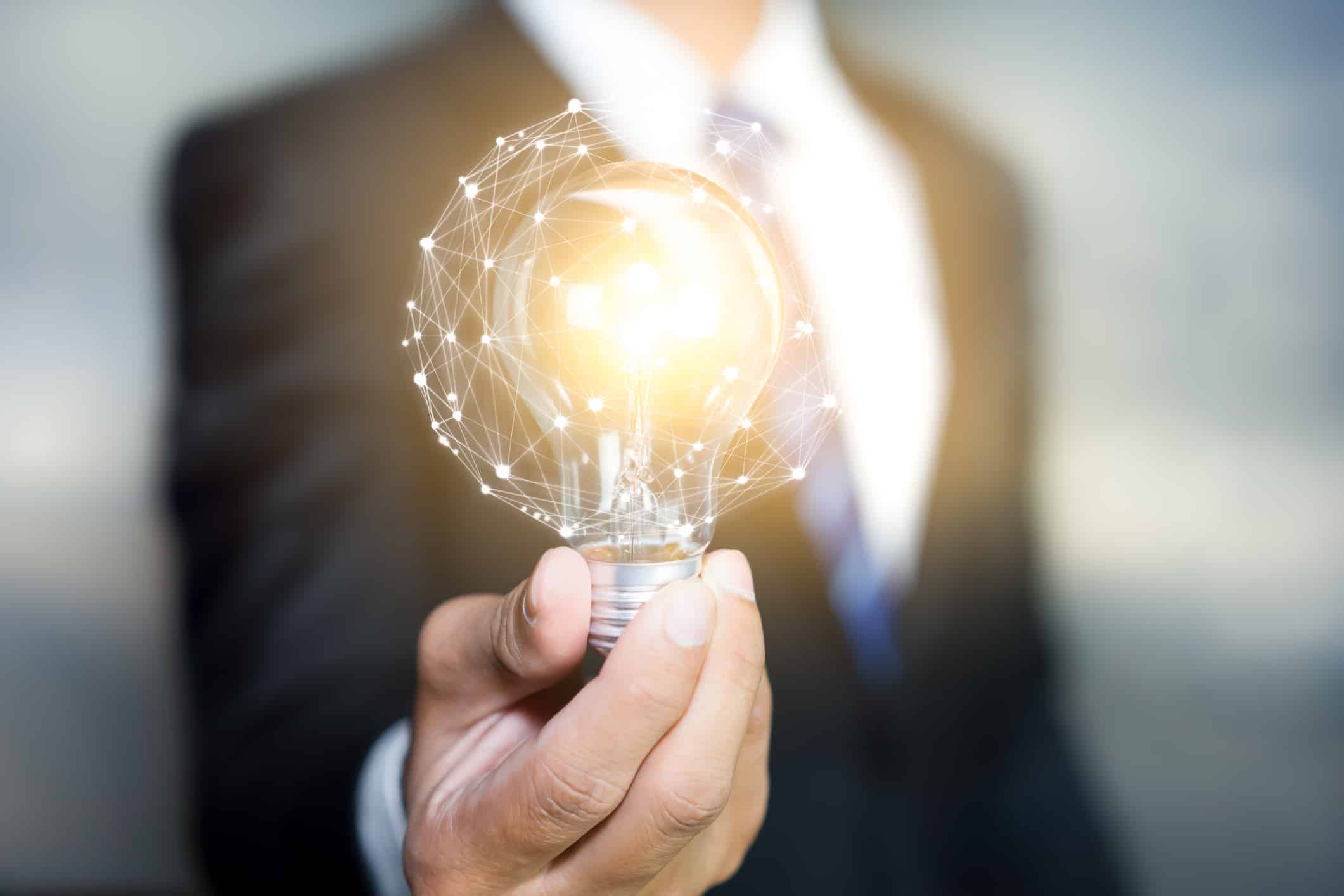 Hand Of Businessman Holding Illuminated Light Bulb, Idea, Innovation And Inspiration Concept.